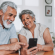 Smiling senior couple sitting at their kitchen table looking at a smartphone together